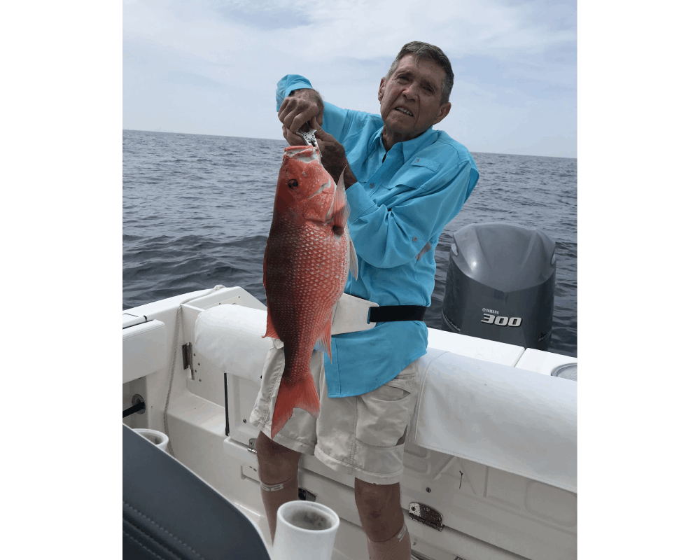 A senior man holding a large fish in a boat