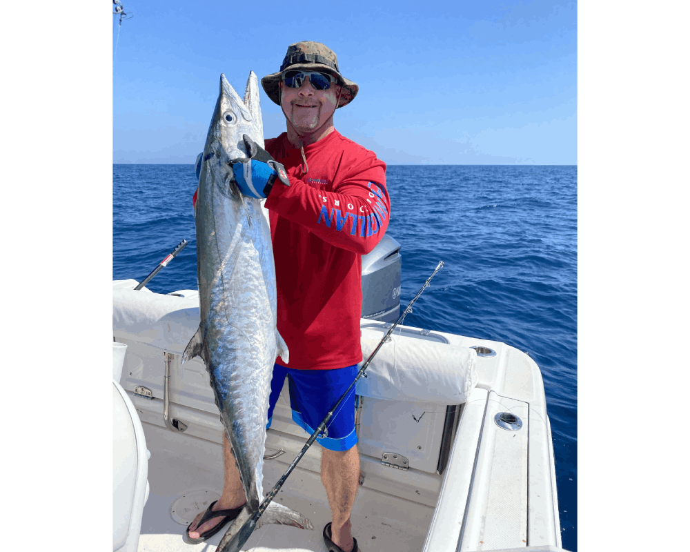 A man wearing a red color shirt holding a fish